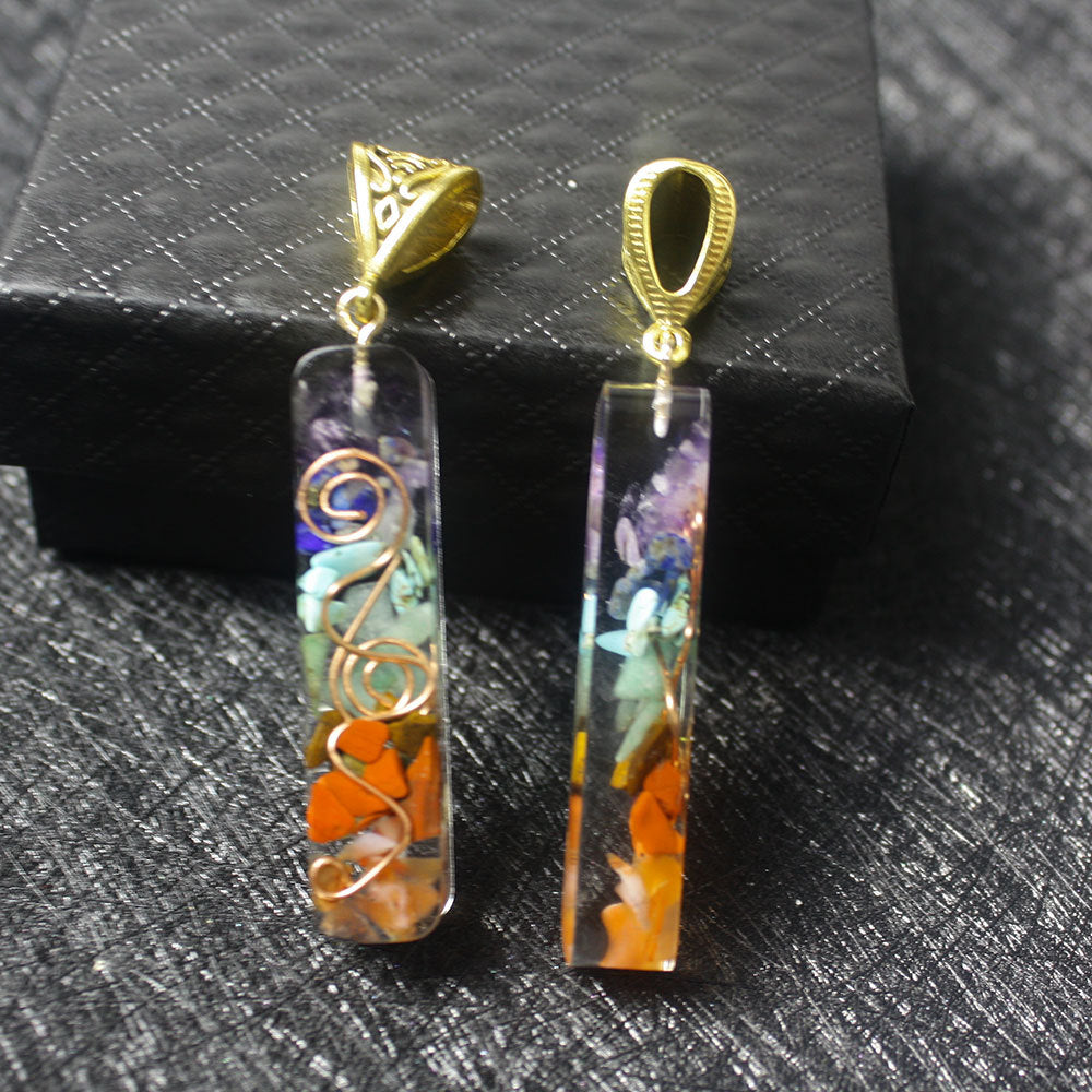 Zwei 7 Chakra Edelstein Anhaenger mit Natursteinsplittern und goldener Fassung auf Geschenkbox